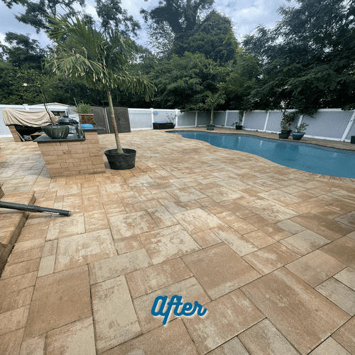 A backyard with a newly renovated pool area featuring interlocking pavers in light and medium brown tones. The pool is surrounded by lush greenery, a white fence, and a few potted plants. Expertly done Paver Restoration Nassau County enhances the beauty. The text "After" is prominently displayed at the bottom of the image.