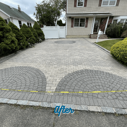 A newly paved driveway featuring a pattern of concentric circles made of grey bricks. The driveway leads up to a white two-story house with brown shutters. Green shrubs and a white fence frame the driveway. A 'caution' ribbon is seen at the bottom. The word "After" is overlaid at the bottom center, showcasing expert Paver Sealing in Nassau County.